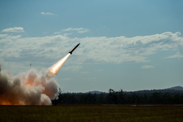 Un intercettore Patriot in volo subito dopo il lancio, sopra il fumo e la vegetazione di un poligono australiano.